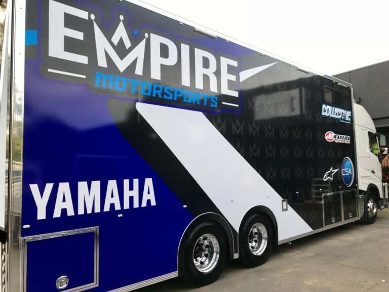 A large truck with “Empire Motorsports” and “Yamaha” prominently displayed in bold blue, white, and black lettering on the side, featuring logos and a modern design.